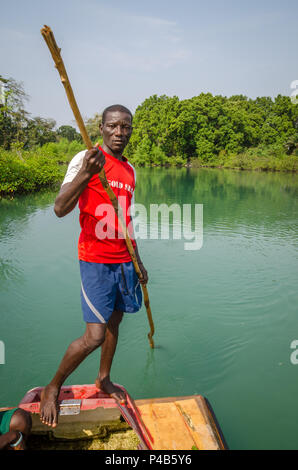 Tokeh Strand, Sierra Leone - 06 Januar, 2014: Unbekannter afrikanischer Mann drückt einfach Floß auf Mangrove Fluss mit Stick. Stockfoto