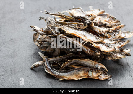 Haufen getrocknete Fische auf schwarzen Stein Hintergrund Stockfoto