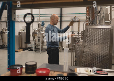 Männliche Arbeiter der Maschine überprüfen der Brennerei Stockfoto