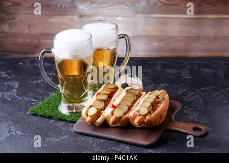 Foto von zwei Tassen mit Bier, Hamburger auf ein Schneidbrett, Fußball Stockfoto