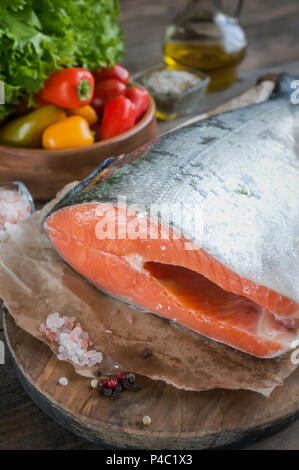 Ein großes Stück Lachs liegt auf einem Holztisch für das Kochen mit einem Messer und einem Gerät für die Reinigung von Fisch. Ernährung Verjüngung des Körpers. Kopieren Sie die spac Stockfoto