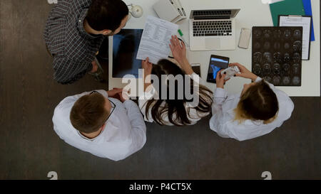 Lächelnd Ärzte, Pillen, die dem Patienten auf Krücken und jubeln ihm bis Stockfoto