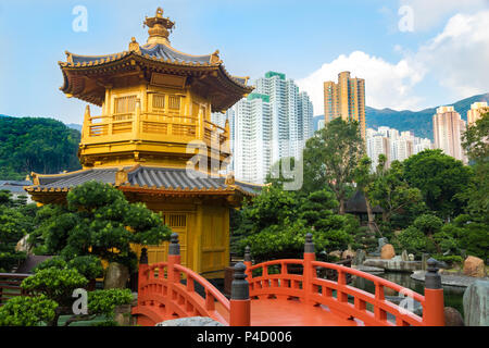 Goldene Pagode in Nan Lian Garden, mit roten Brücke und von grünen Pflanzen umgeben. Die Hong Kong Skyline im Hintergrund. Stockfoto