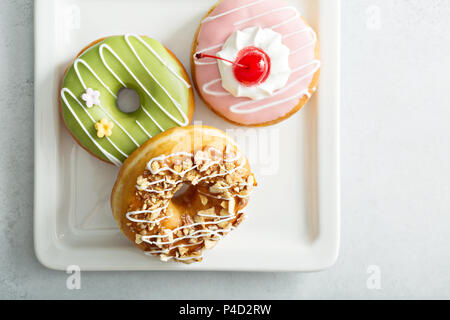 Sortierte glasiert gebratene Donuts auf einer Platte Stockfoto