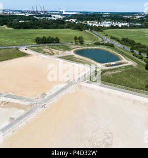 Schräg Luftbild der Baustelle für eine neue Entwicklung mit einem großen gefüllt regen Rückhaltebecken, in der Nähe von Wolfsburg. Stockfoto