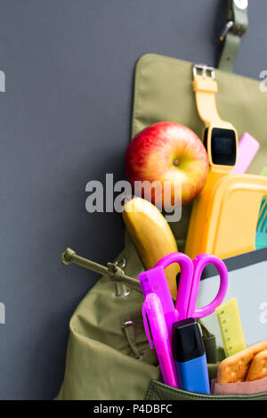 Rucksack mit Schulmaterial auf schwarzem Hintergrund. Ansicht von oben Flach Stockfoto