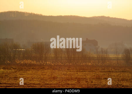 Warme dunstig Sonnenaufgang über dem Dorf. Polen, das Heilige Kreuz Berge. Stockfoto
