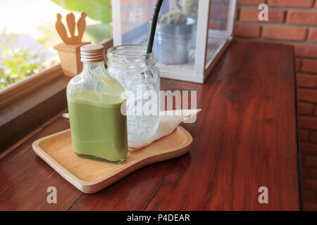 Hot Matcha grüner Tee in der Flasche und Eis im Glas auf Holz Tisch, Wand Hintergrund im Vintage Cafe, trinken Sommer. Stockfoto