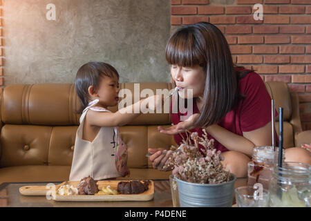 Asiatische Cute Baby und Mutter genießen eatting Schokolade Lava in das Cafe gesetzt Stockfoto