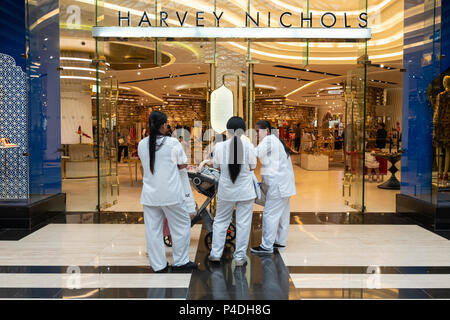 Weibliche Zimmermädchen warten draußen Harvey Nichols in der Prestige Mall innerhalb der Avenues Shopping Mall in Kuwait City, Kuwait. Stockfoto