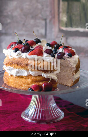 Schöne angelfood Kuchen mit Schlagsahne und frischen bunten Beeren bedeckt Stockfoto