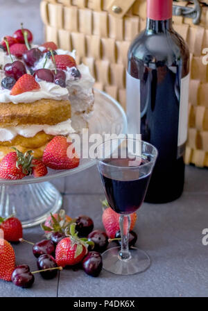 Rotwein mit einem frischen Engel essen Kuchen in den Beeren bedeckt. ein leckeres Picknick! Stockfoto