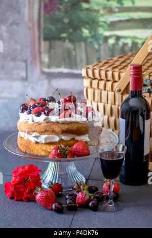 Romantisches Picknick mit einem hausgemachten Angel Food cake in Sahne und frischen Beeren bedeckt, und eine Flasche Wein. Stockfoto