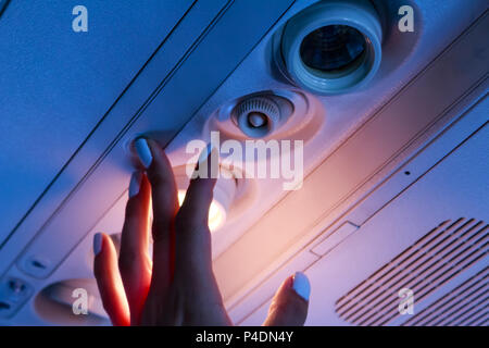 Der Passagier hand closeup schalten Sie das Licht im Flugzeug Stockfoto