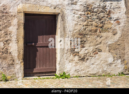 Eine hölzerne Tür in der Mauer eines alten Hauses in Mitteleuropa. Stockfoto