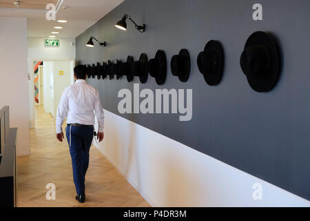 Ein ultra-orthodoxer Jude kommt an traditionellen Haredi-Hüten vorbei, die an einer Wand in einem Korridor eines Bürogebäudes in der Stadt Bnei Brak oder Bene Beraq, einem Zentrum des Haredi-Judentums in Israel, hängen Stockfoto