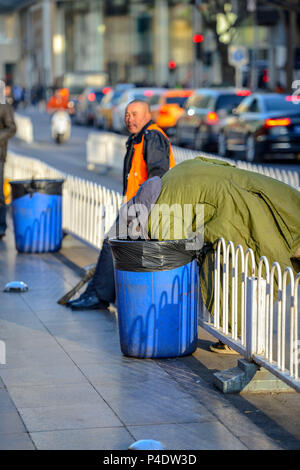 Peking, China - 11. MÄRZ 2016: Obdachlose in einem Müll Box auf der Suche nach Essen. Stockfoto