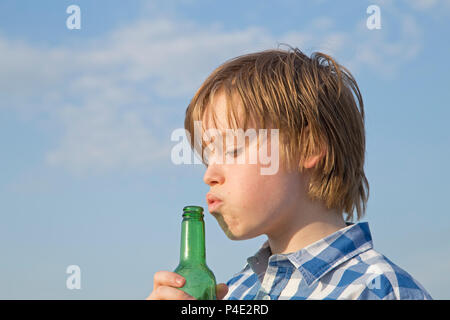Porträt eines Jungen das Blasen auf einer Flasche Stockfoto