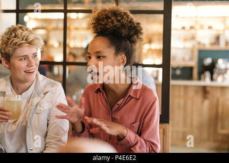 Junge Frau mit Freunden zu reden über Getränke in einem Cafe Stockfoto