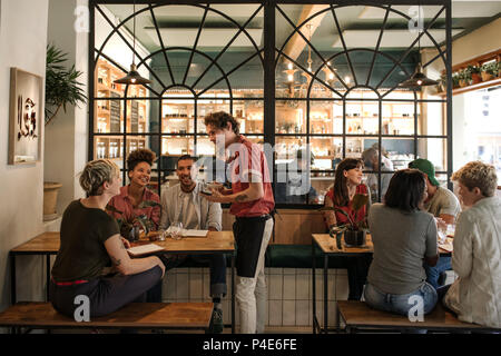 Kellner, die Aufträge von Kunden in einem Bistro sitzen Stockfoto