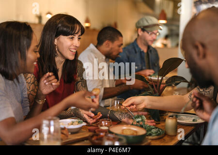 Lächelnden jungen Freunde genießen Sie ein gemeinsames Abendessen in einem trendigen Bistro Stockfoto
