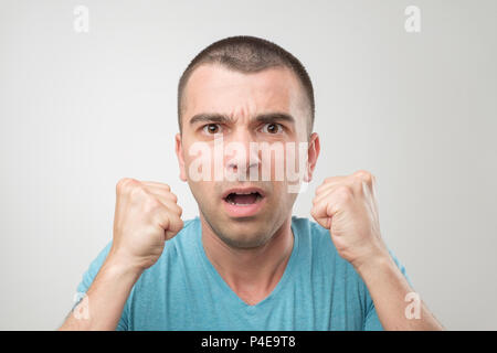 Junge Hispanic Mann im blauen Hemd feiern Sieg seiner Mannschaft über grauen Hintergrund. Fußball-Fan Konzept Stockfoto