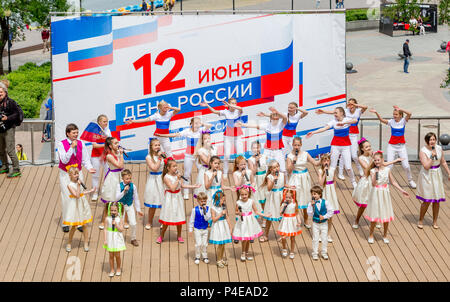 Russland, Wladiwostok, 06/12/2018. Childs in bunten Garnituren als Russische Fahne gemalt durchführen Song auf der Bühne. Feier der jährlichen Russland Tag auf Juni Stockfoto