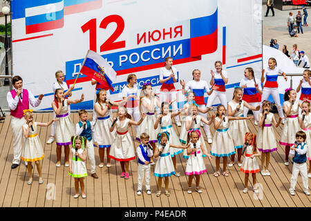 Russland, Wladiwostok, 06/12/2018. Childs in bunten Garnituren als Russische Fahne gemalt durchführen Song auf der Bühne. Feier der jährlichen Russland Tag auf Juni Stockfoto