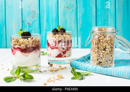 Gesunde 2-in-1-Dessert mit Joghurt, Müsli, Marmelade, Black, Glas auf Holz Hintergrund. Stockfoto