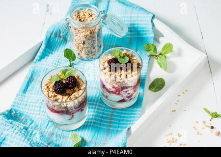 Gesunde 2-in-1-Dessert mit Joghurt, Müsli, Marmelade, Black, Glas auf Holz Hintergrund. Stockfoto