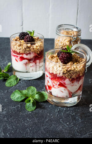 Gesunde 2-in-1-Dessert mit Joghurt, Müsli, Marmelade, Black in Glas und Stein Stockfoto