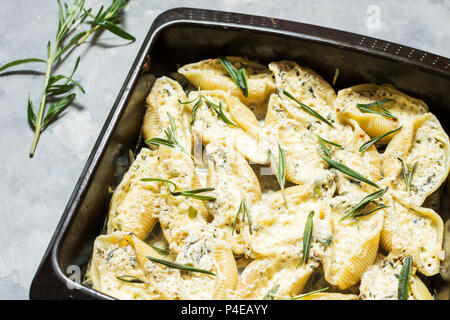 Italienische Pasta Conchiglioni Rigati gefüllt mit Käse und Grüns auf konkrete Tabelle. Stockfoto