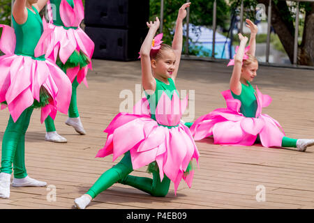 Russland, Wladiwostok, 06/12/2018. Schönes, kleines Mädchen in lustigen Kostümen von Lotus Blumen führen den Tanz auf der Bühne. Feier der jährlichen Russland Tag auf Stockfoto