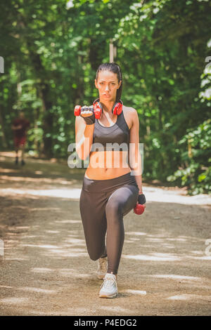 Schöne Sportlerin üben mit Hanteln in der Natur. Stockfoto