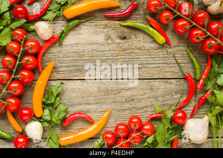 Mischung aus Chili Pepper Cherry Tomaten auf einem Zweig Knoblauch und andere Gewürze auf einem hölzernen Kopie Raum Hintergrund. Stockfoto