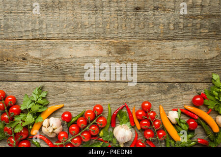 Mischung aus Chili Pepper Cherry Tomaten auf einem Zweig Knoblauch und andere Gewürze auf einem hölzernen Kopie Raum Hintergrund. Stockfoto