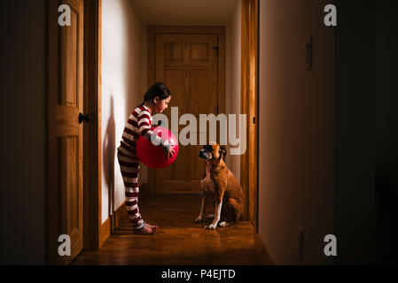 Stehendes Mädchen im Flur mit einem riesigen Ball spielen mit Ihrem Hund Stockfoto