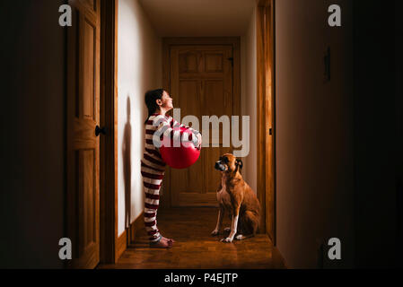 Stehendes Mädchen im Flur mit einem riesigen Ball spielen mit Ihrem Hund Stockfoto