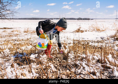 Junge auf eine Ostereiersuche im Schnee Stockfoto