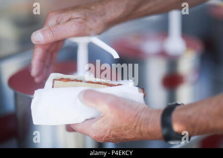 Mann, Tomatensauce auf einem Hotdog Stockfoto