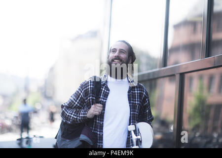 Lächelnd Mann auf der Straße mit einem Skateboard Stockfoto