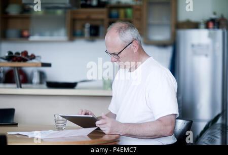 Mann an einem Tisch sitzen mit einem digitalen Tablet Stockfoto
