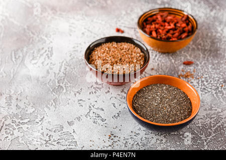 Super Foods - Chia Samen, Leinsamen und Goji Beeren in drei Keramikschalen Stockfoto