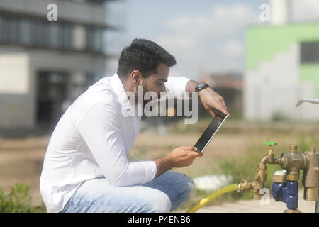Mann sitzt im Freien, ein Foto von einem Hydranten mit einem digitalen Tablet Stockfoto