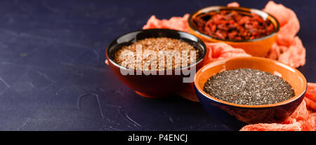 Super Foods - Chia Samen, Leinsamen und Goji Beeren in drei Keramikschalen Stockfoto