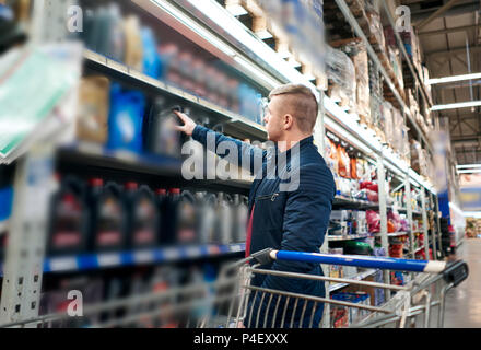 Der Mann mit der Karre im Store beschließt das Auto Öl Stockfoto