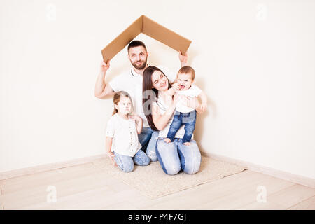 Glückliche junge Familie unter einem sicheren Dach, Konzept Stockfoto