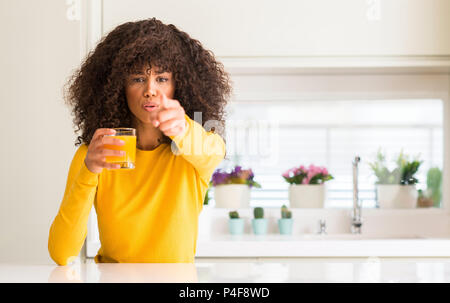 Afrikanische amerikanische Frau trinkt Orangensaft in ein Glas mit Finger auf die Kamera und zu Ihnen zeigt, Handzeichen, positiv und zuversichtlich Geste von Stockfoto