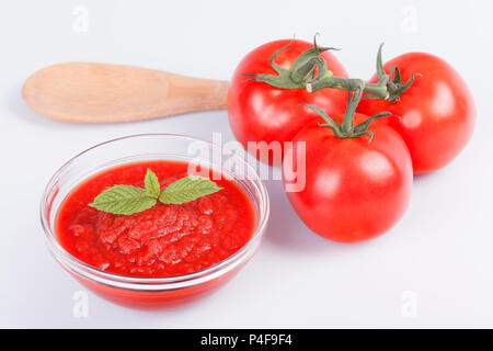 Eine Schüssel mit pürierten Tomaten mit Tomaten isoliert auf Weiss. Stockfoto