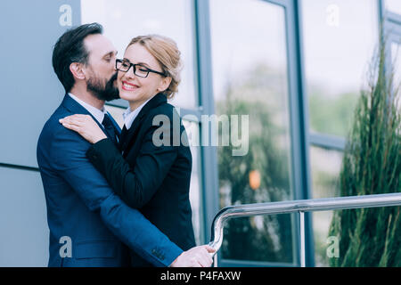Gerne gestandene Geschäftsleute Umarmen und Küssen, während draußen stehen Stockfoto